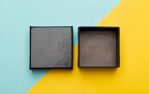 Mini black box product packaging isolated on yellow half blue background. F.. Stock Photos