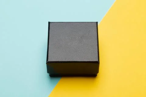 Mini black box product packaging isolated on yellow half blue background Stock Photos