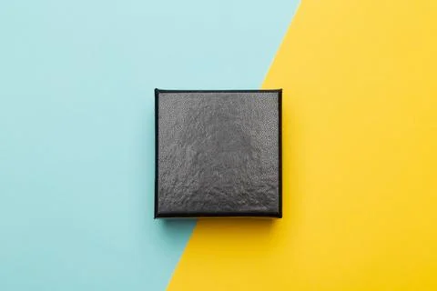 Mini black box product packaging isolated on yellow half blue background. F.. Stock Photos
