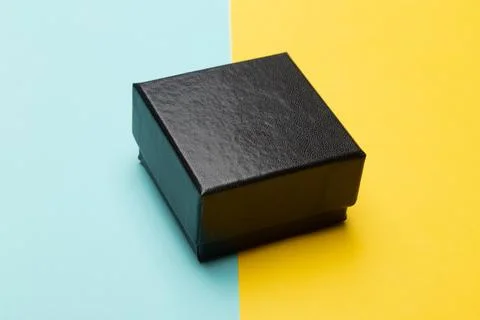 Mini black box product packaging isolated on yellow half blue background Stock Photos