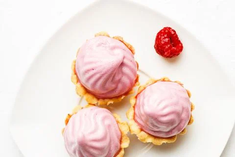 Mini cakes baskets with raspberry cream on white plate Stock Photos