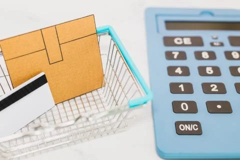 Mini cardboard delivery parcel box into shopping basket with payment card and Foto stock