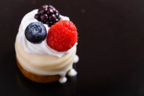 Mini cheesecake with berries and cream on a black background Stock Photos