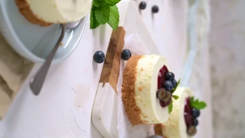 Mini cheesecakes with berry compote and fresh mint on a white textured surface Stock Footage 341366020
