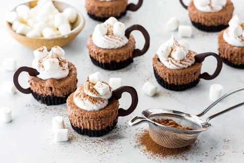 Mini cheesecakes in the shape of cups of hot cocoa with cream and marshmallows. Stock Photos