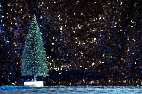 Mini Christmas tree on sequin and knit background Stock Photos