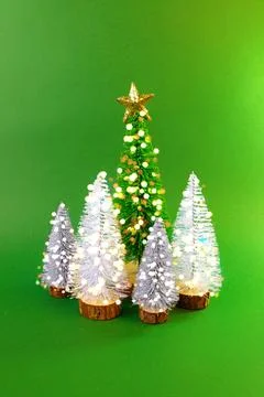 Mini Christmas trees with soft glowing lights on a vibrant green background Stock Photos