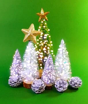 Mini Christmas trees with soft glowing lights on a vibrant green background Stock Photos