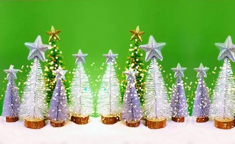 Mini Christmas trees with soft glowing lights on a vibrant green background, Stock Photos