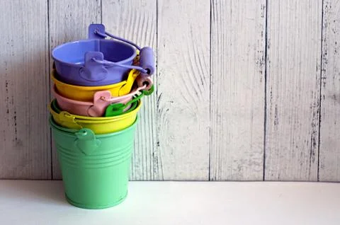 Mini colored tin pails or buckets on wooden background with copy space Stock Photos