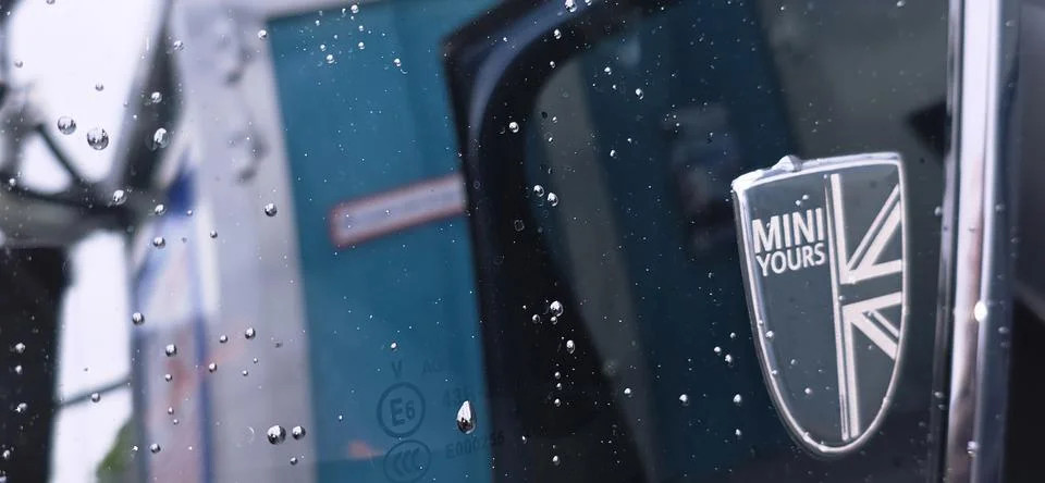 Mini Cooper logo on wet window with raindrops and blurred background Stock Photos