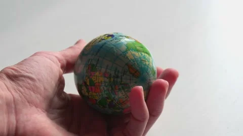 A mini copy of a globe lies in the hands closeup. The hand or hands are play Stock Footage 152581258