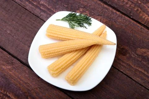 Mini Corn cob preserved on plate on wooden board. Stock Photos