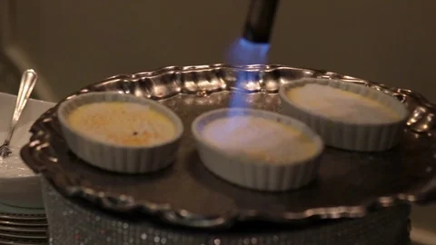 Mini creme brulee being toated with flame close Stock Footage 91294940