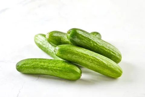 Mini cucumbers on white marble, ready to cook and eat Stock Photos