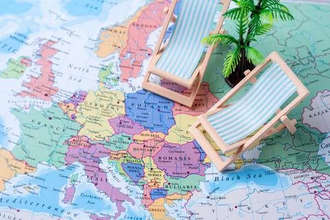 Mini deck chairs and palm tree on Europe map travel concept Stock Photos
