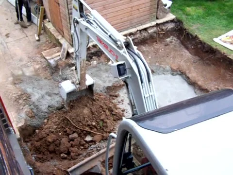 Mini digger in a domestic garden excavating Stock Footage