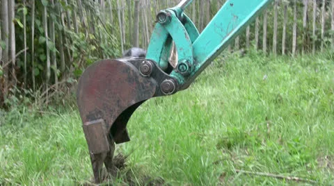 A Mini digger excavating a trench on grassy land breaking into the grass Video stock 25509900