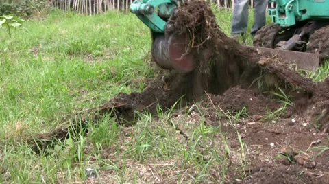 A Mini digger excavating a trench on grassy land unearths metal Stock Footage 25510047