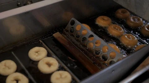 Mini Donut Machine flipping donuts in deep frying oil Stock Footage 113086993
