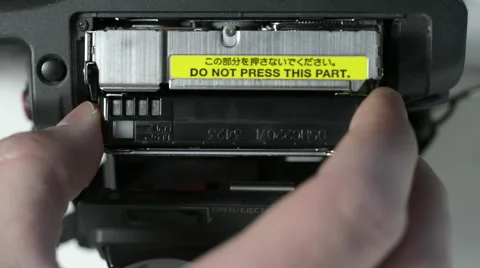 Mini DV tape being ejected and inserted into a camera Stock Footage 50673049