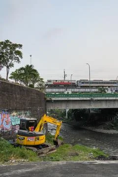 A mini excavator and a train crossing a concrete bridge. 스톡 사진