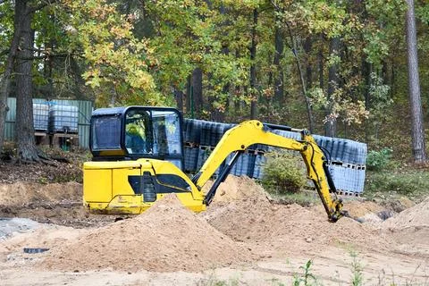 Mini excavator at construction site surrounded by trees. Compact constructi.. Foto stock