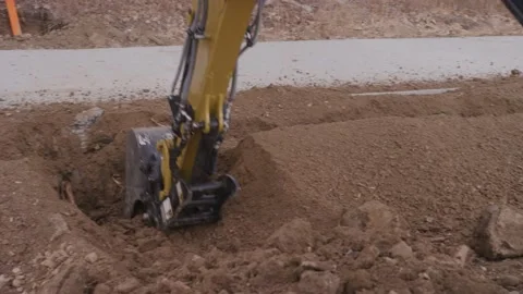 Mini excavator digging hole in dirt by sidewalk on construction site Stock Footage 227450029