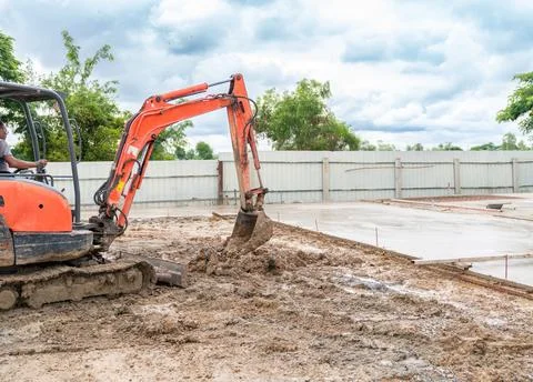 Mini excavator digging through soil for adjust ground level. Stock Photos