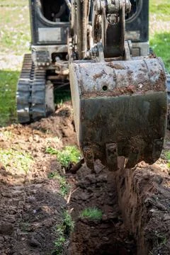 Mini excavator digs a pit or trench for communications Stock Photos