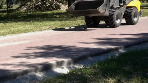 A mini excavator drives along the path of the spring park. Stock Footage 135754455
