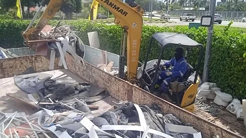 A mini excavator operator loads rubbish from a landfill into a truck Stock Footage 304337567