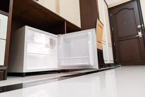 Mini fridge in low angle view, inside its empty shelves placed under wooden.. Stock Photos