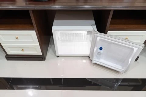 Mini fridge in low angle view, inside its empty shelves placed under wooden.. Stock Photos