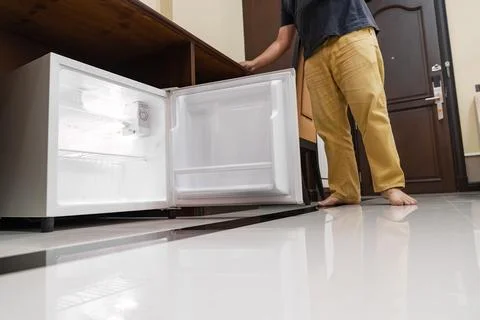 Mini fridge in low angle view, inside its empty shelves placed under wooden.. Stock Photos