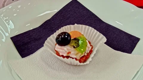 Mini fruit dessert with cream, kiwi, grape, and jelly on a plate Stock Footage 332558567