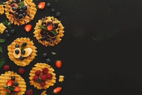 Mini fruit tartlets with berries and cream on black background Stock Photos