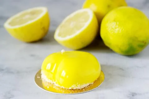 Mini glazed mousse lemon cake decorated with beads and coconut chips. Stock Photos