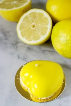 Mini glazed mousse lemon cake decorated with beads and coconut chips. Stock Photos