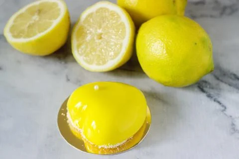 Mini glazed mousse lemon cake decorated with beads and coconut chips. Stock Photos