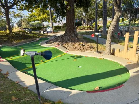 Mini-golf course with multiple holes and obstacles surrounded by greenery. Stock Photos