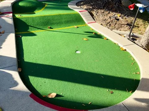 Mini-golf course with multiple holes and obstacles surrounded by greenery. Stock Photos