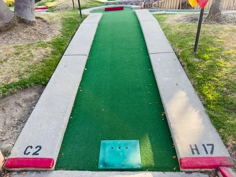 Mini-golf course with multiple holes and obstacles surrounded by greenery. Stock Photos