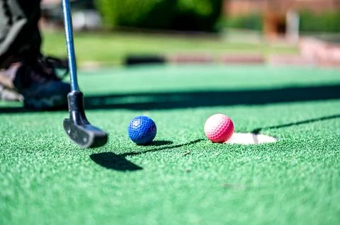 Mini golf game with several colored balls in the way of a putter lined up. 스톡 사진