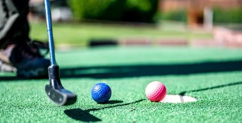 Mini golf game with several colored balls in the way of a putter lined up. Stockfoto's