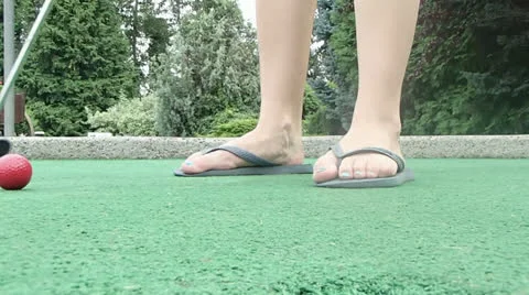 Mini golf putting in sandals Stock Footage 22475799
