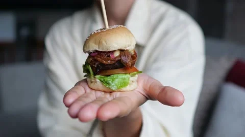 A mini hamburger in the palm of your hand with a delicious filling of vegetables Stock Footage 200384944