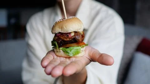 A mini hamburger in the palm of your hand with a delicious filling of vegetables Stock Photos