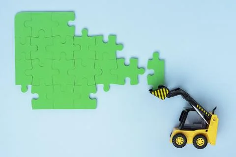 Mini loader successfully folding puzzle on a white background. Foto stock