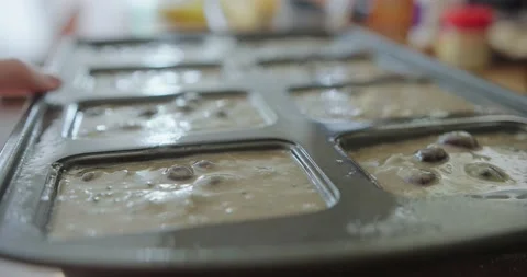 A mini loaf pan filled with blueberry zucchini bread batter is pulled away Stock Footage 202520555